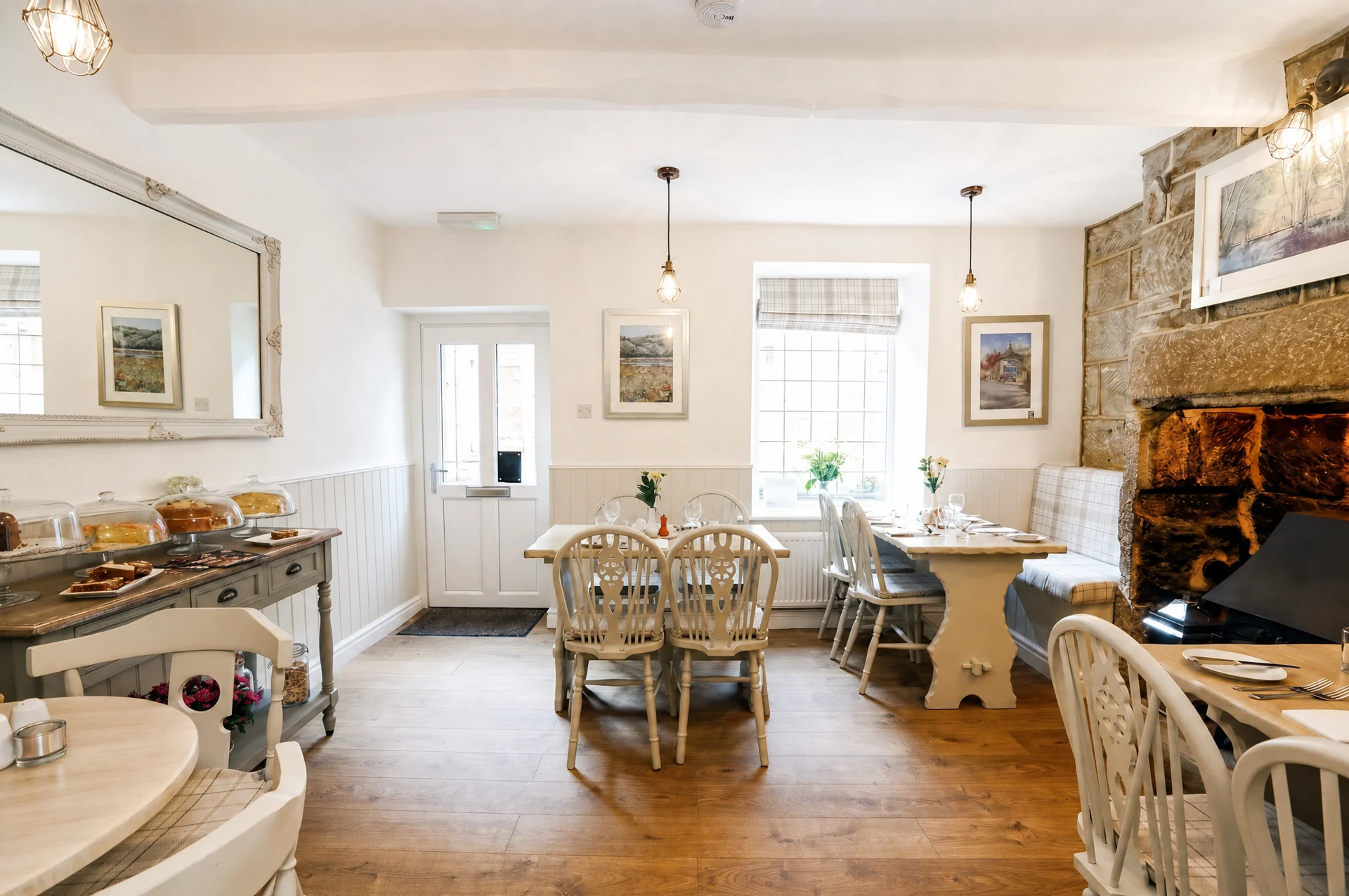 The Willow dining room, with cream chairs, a stone fireplace and bright natural light